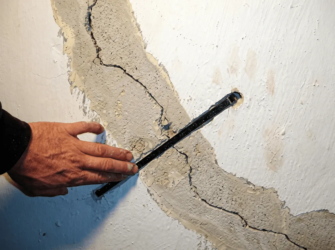 A wall with a large crack is being inspected by a professional in Lakeland, FL